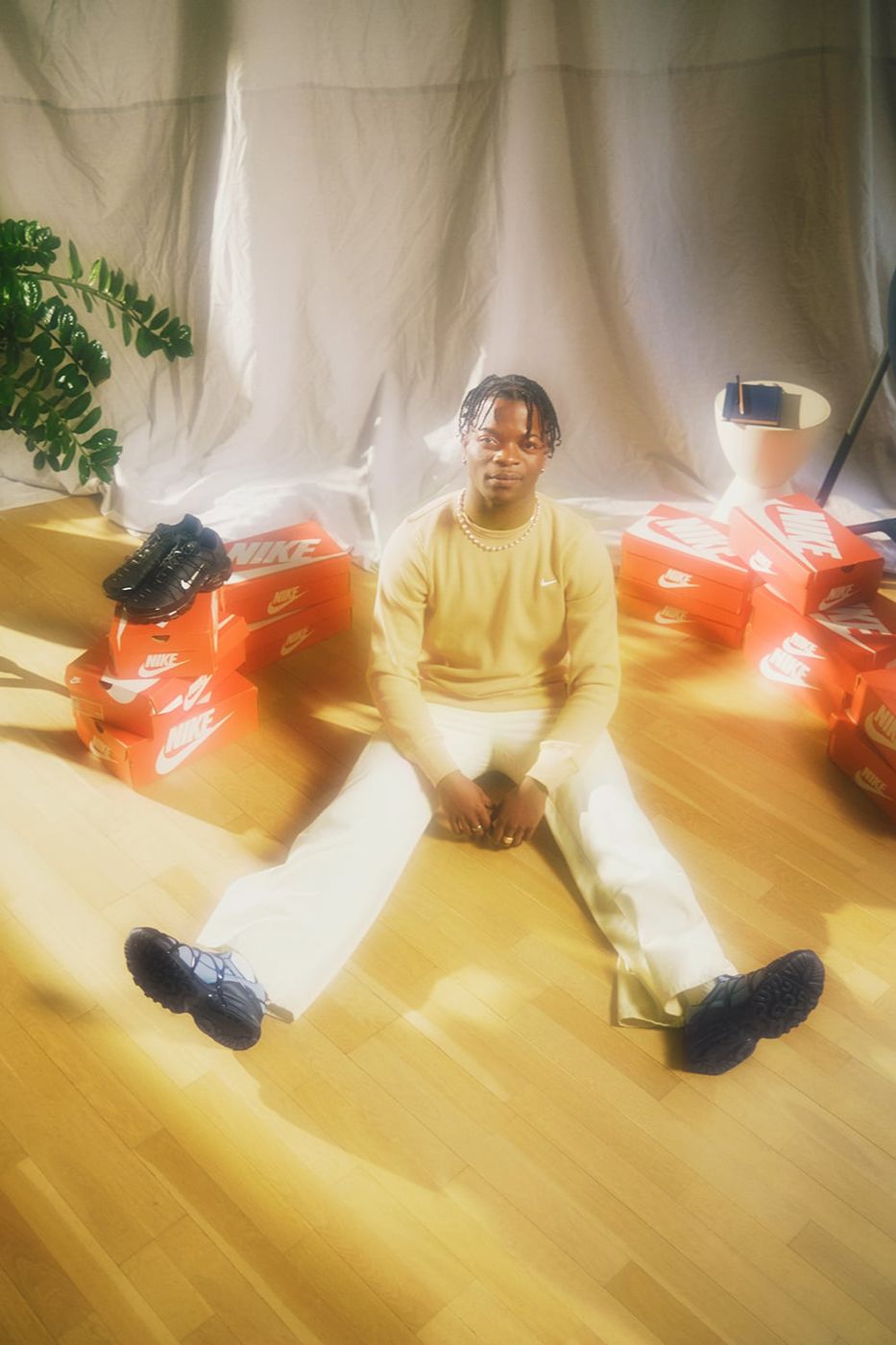 Taofeek Abijako seated with Nike shoe boxes